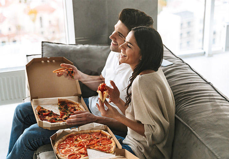 pareja viendo tele con pizza