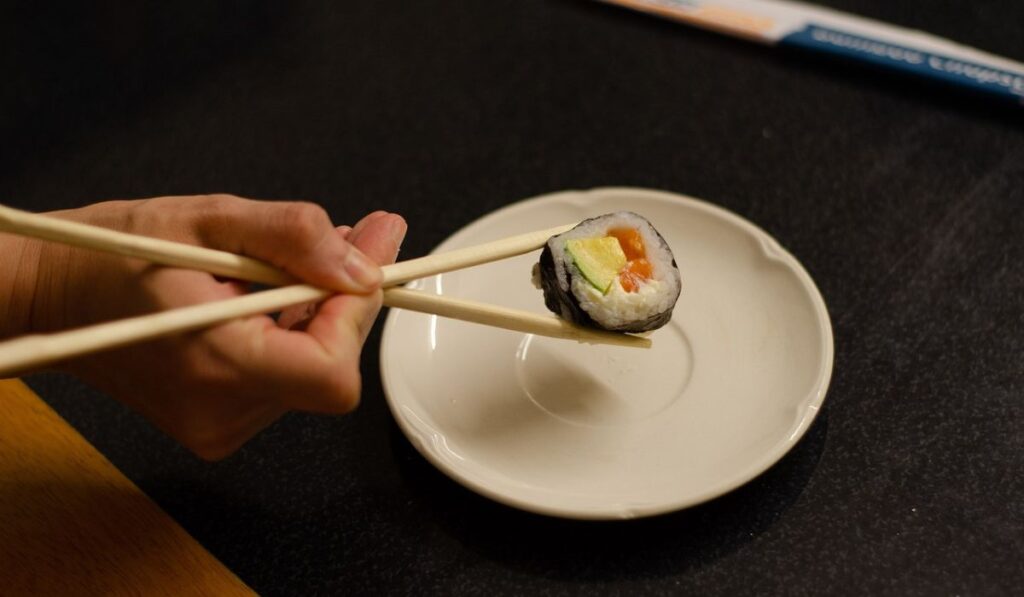Comer sushi con palitos, forma correcta. 