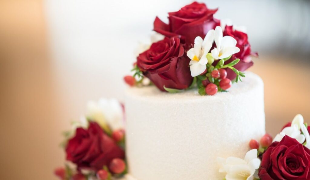 Piso alto de pastel de boda con rosas rojas. 