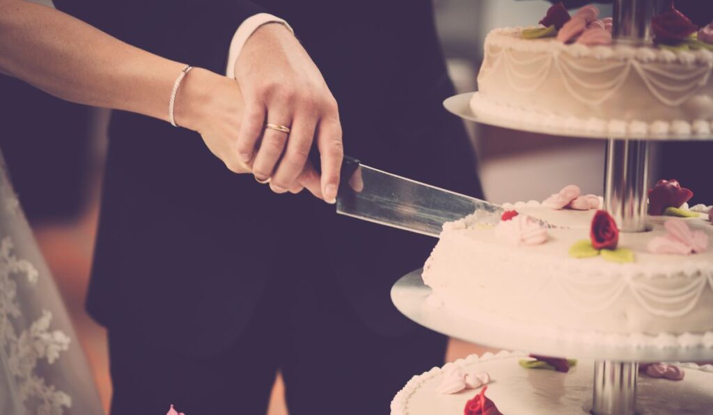 Pareja cortando pasteles de boda decorados.