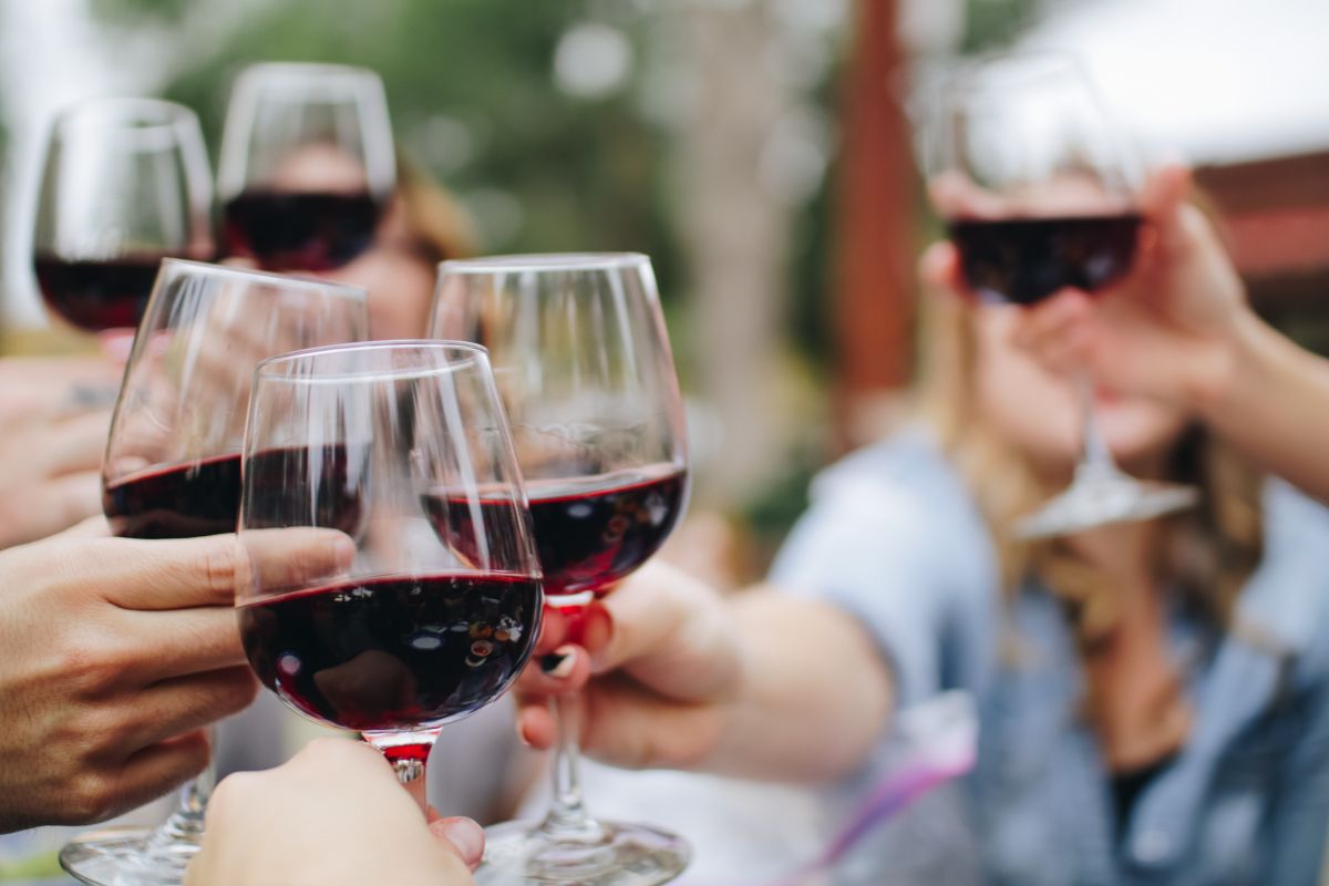 Personas brindando con vino tinto. Foto de Canva.