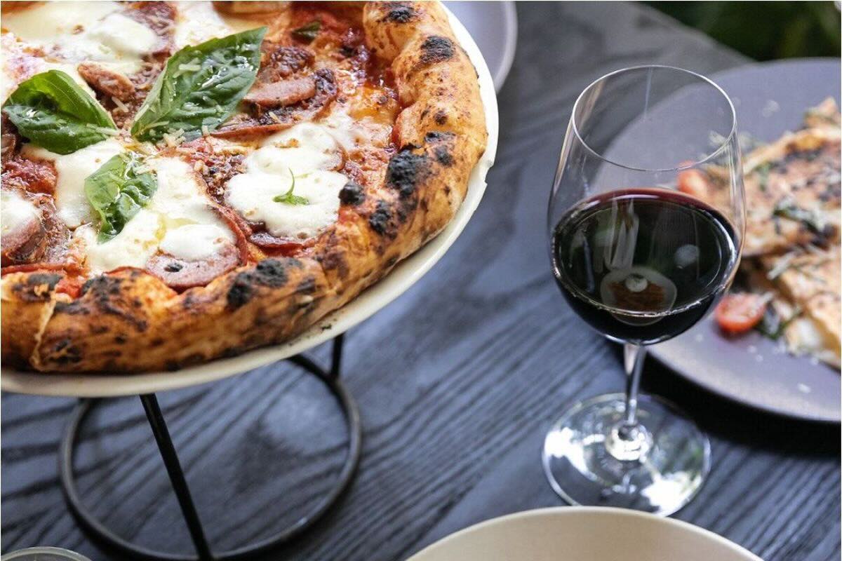 Pizza completa acompañada con vino tinto. Foto de Instagram Fratelli La Bufala.