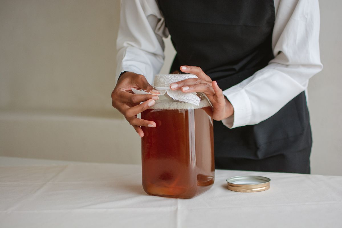Persona cubriendo frasco con tela para fermentación. Foto de Canva.