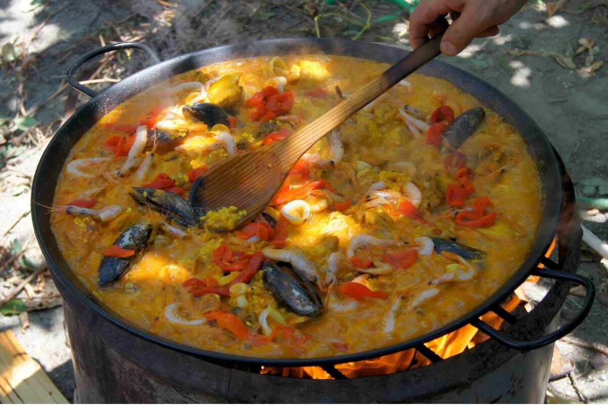 Persona cocinando paella tradicional. Foto de Wikimedia Commons.