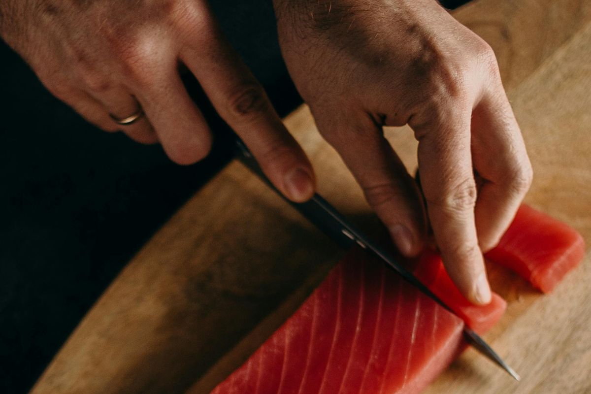 Persona cortando atún fresco. Foto de Pexels.