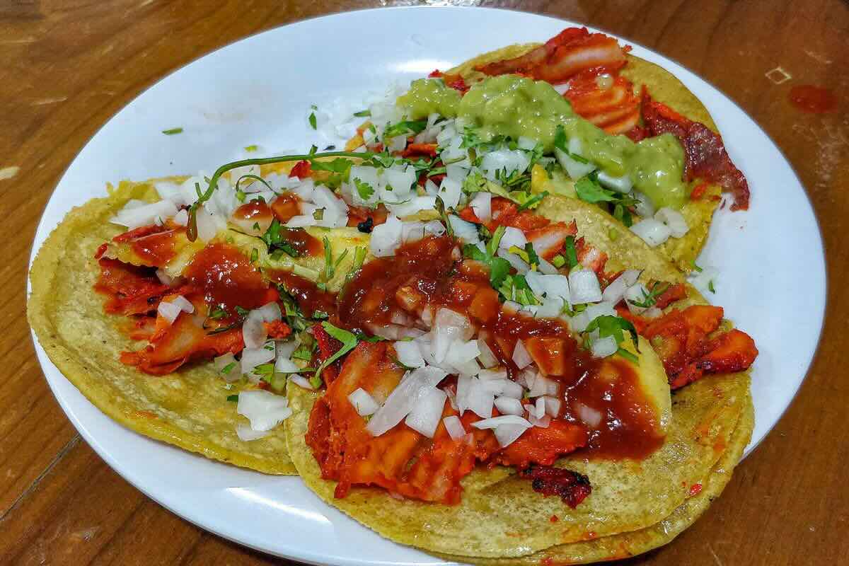 Tacos al pastor preparados con cebolla y cilantro fresco. Foto de Flickr.