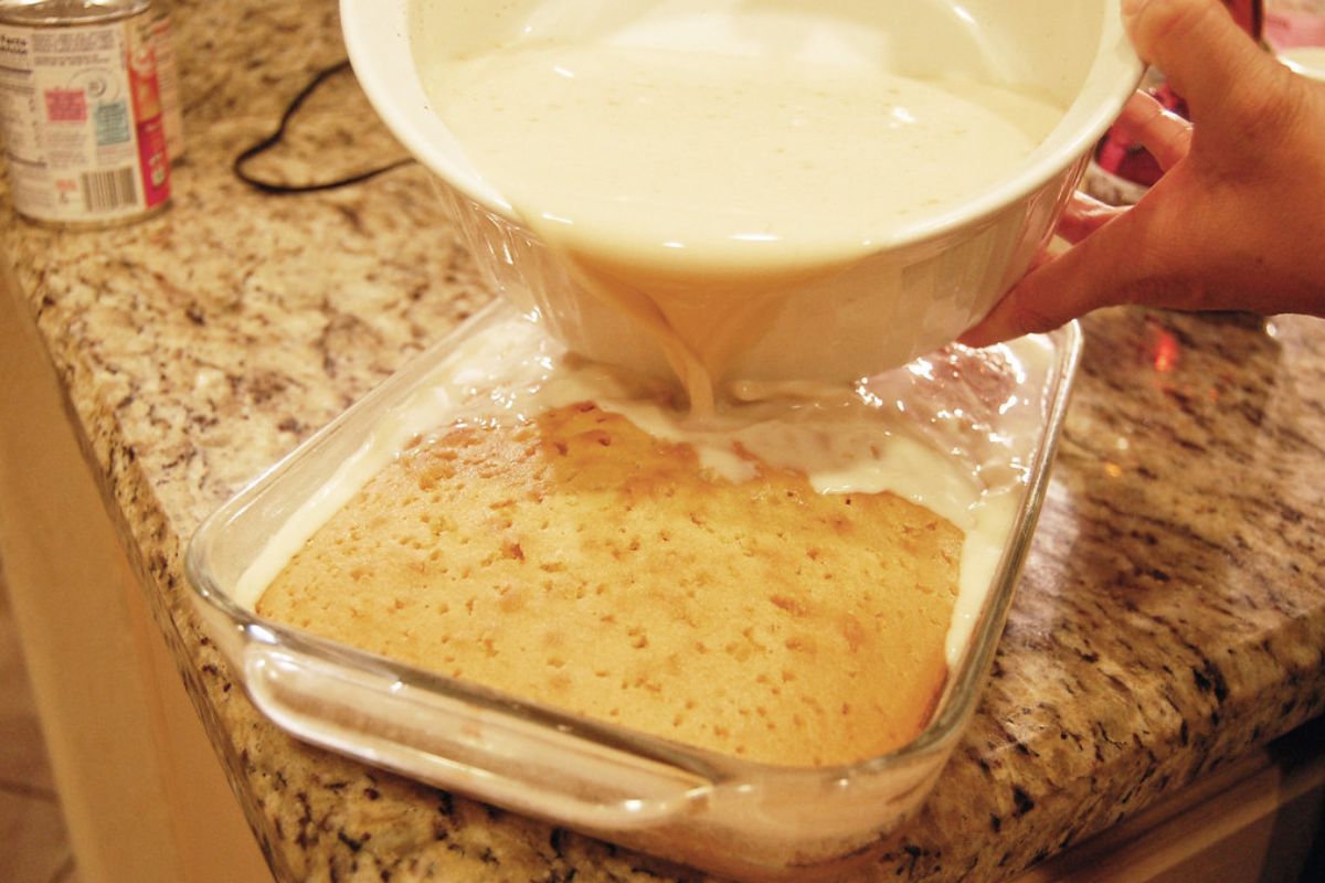 Persona hidratando bizcocho de vainilla con mezcla de leche. Foto de Flickr.
