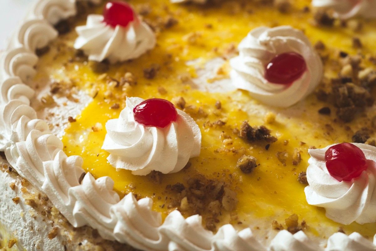 Pastel decorado con crema batida, cerezas y mermelada de mango. Foto de PxHere.