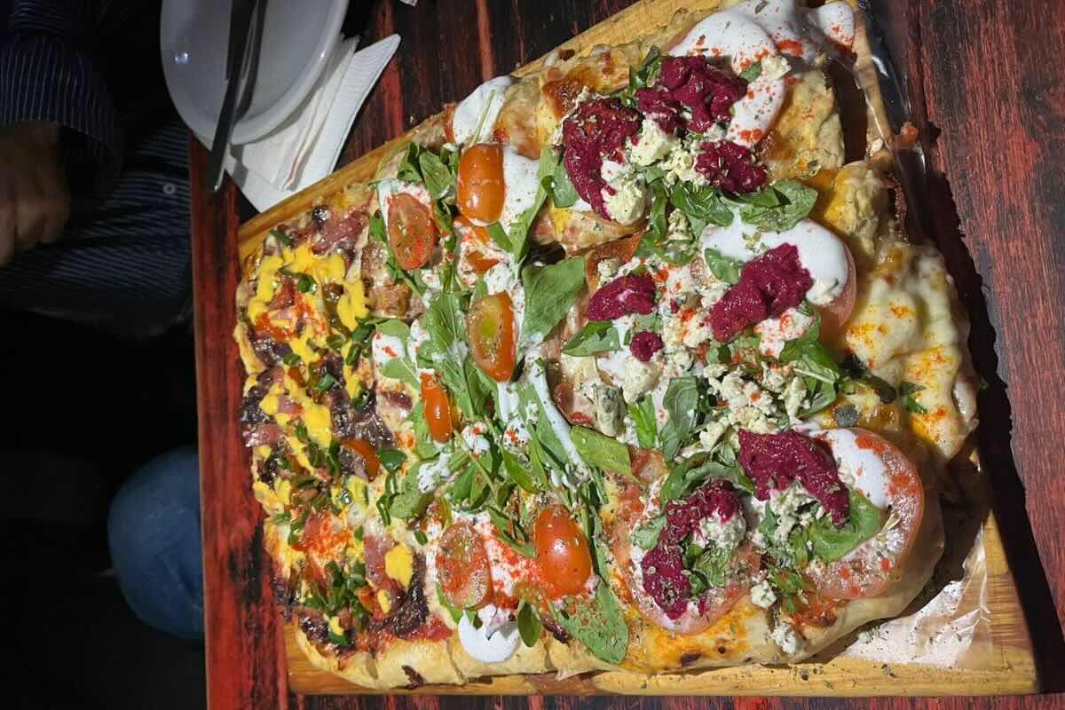 Pizza rectangular con diversos ingredientes. Foto por Tali Akuka.