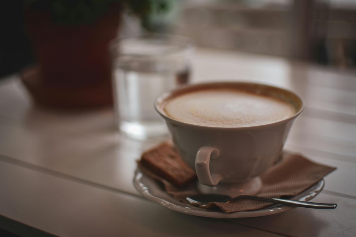 Taza de café con leche acompañada de galletas. Foto de Pexels.