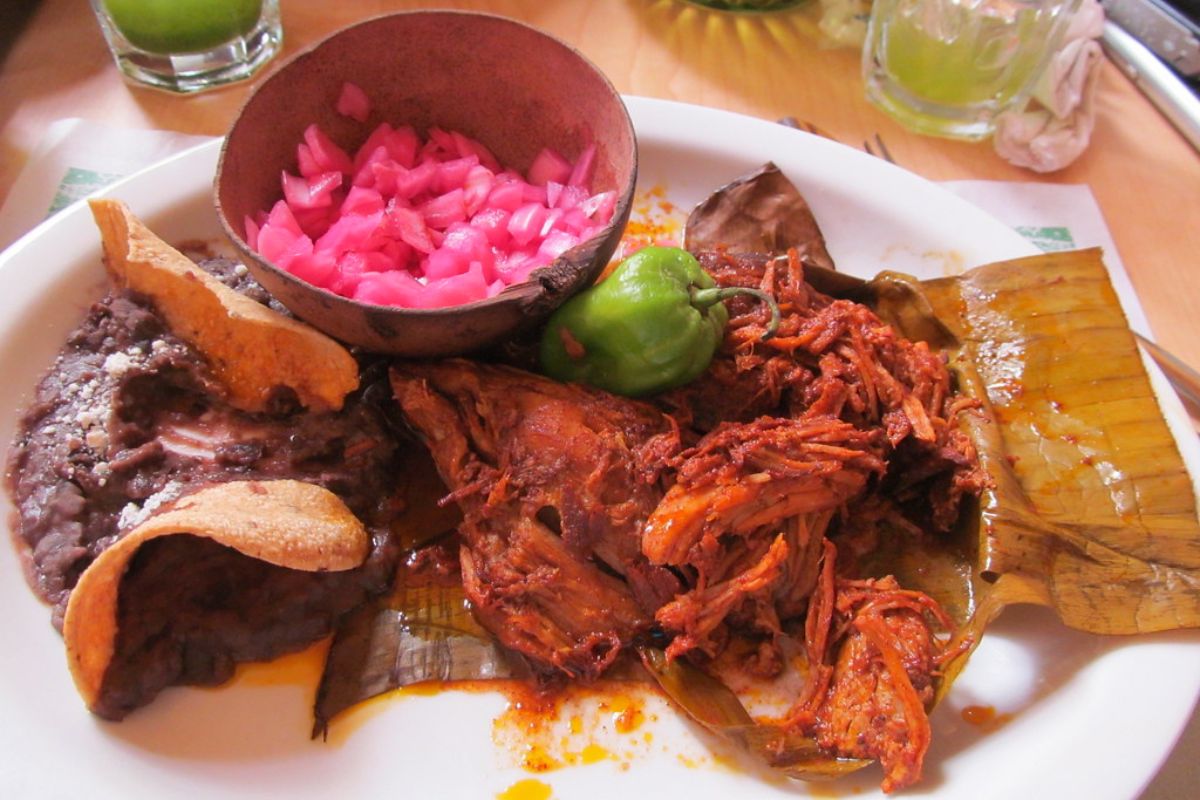 Cochinita pibil acompañada con frijoles refritos y encurtido de cebolla morada. Foto de Flickr.