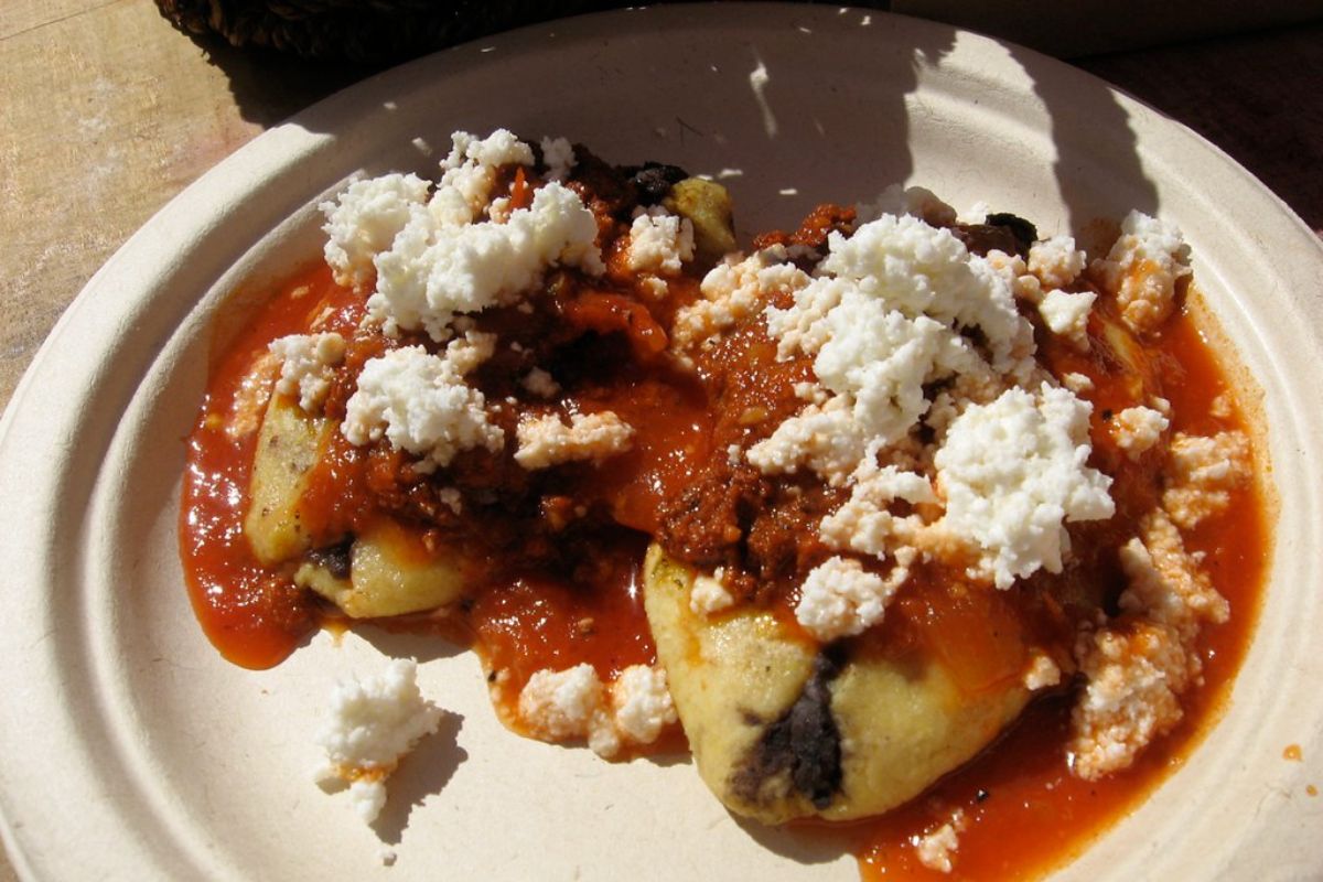 Tlacoyos bañados en salsa roja, acompañados de queso fresco. Foto de Flickr.