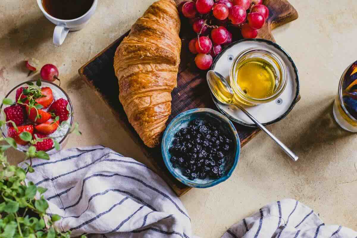 Desayuno con pan dulce y fruta fresca. Foto de Pexels.