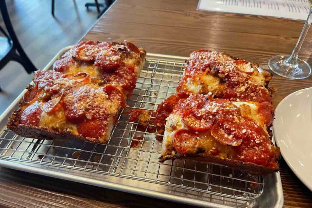 La pizza estilo Detroit se presenta en forma rectangular y es más gruesa que las pizzas tradicionales.