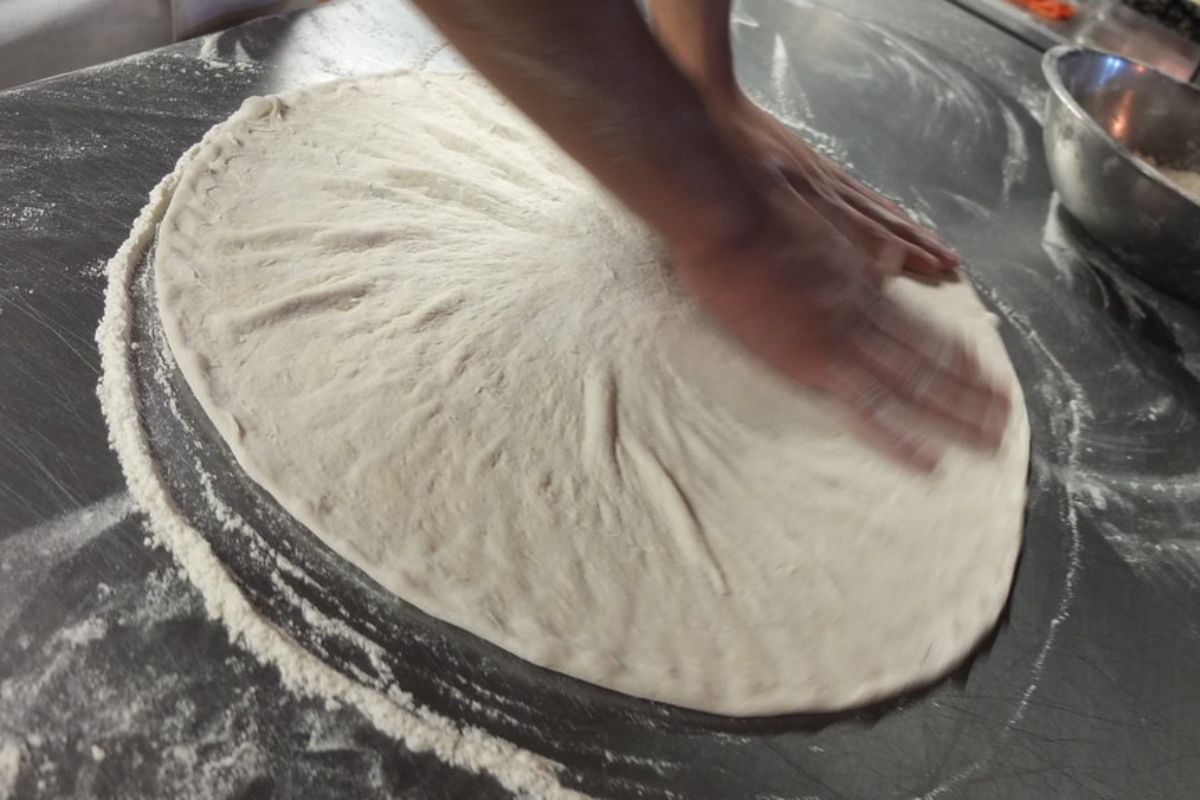 Persona preparando base de pizza. Foto de Flickr.