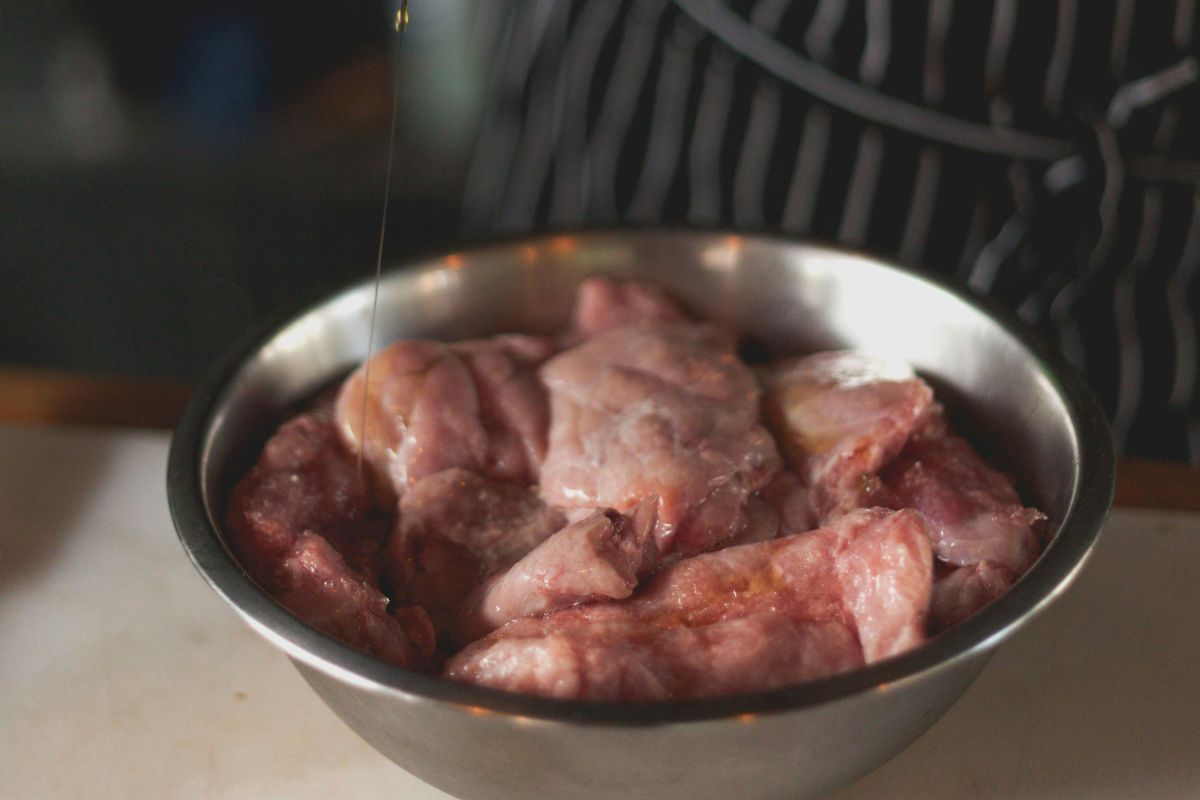 Persona marinando pollo. Foto de Pexels.