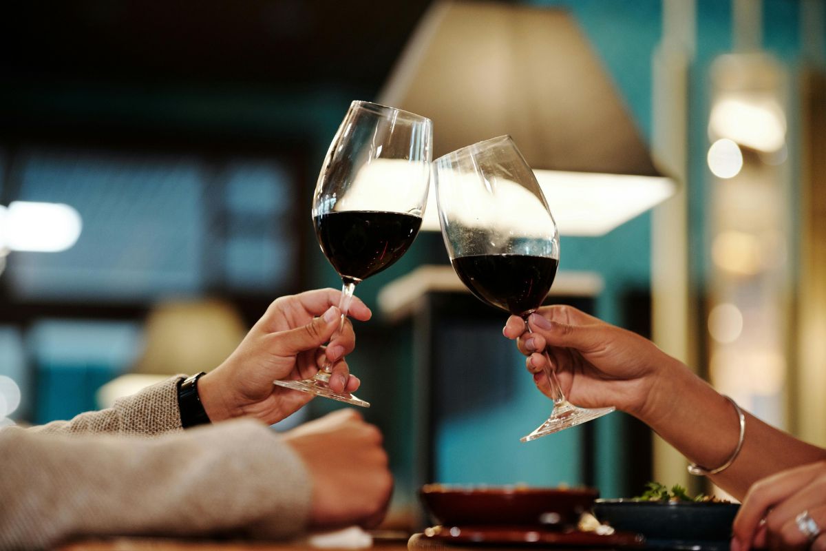 Personas brindando con vino tinto. Foto de Pexels.