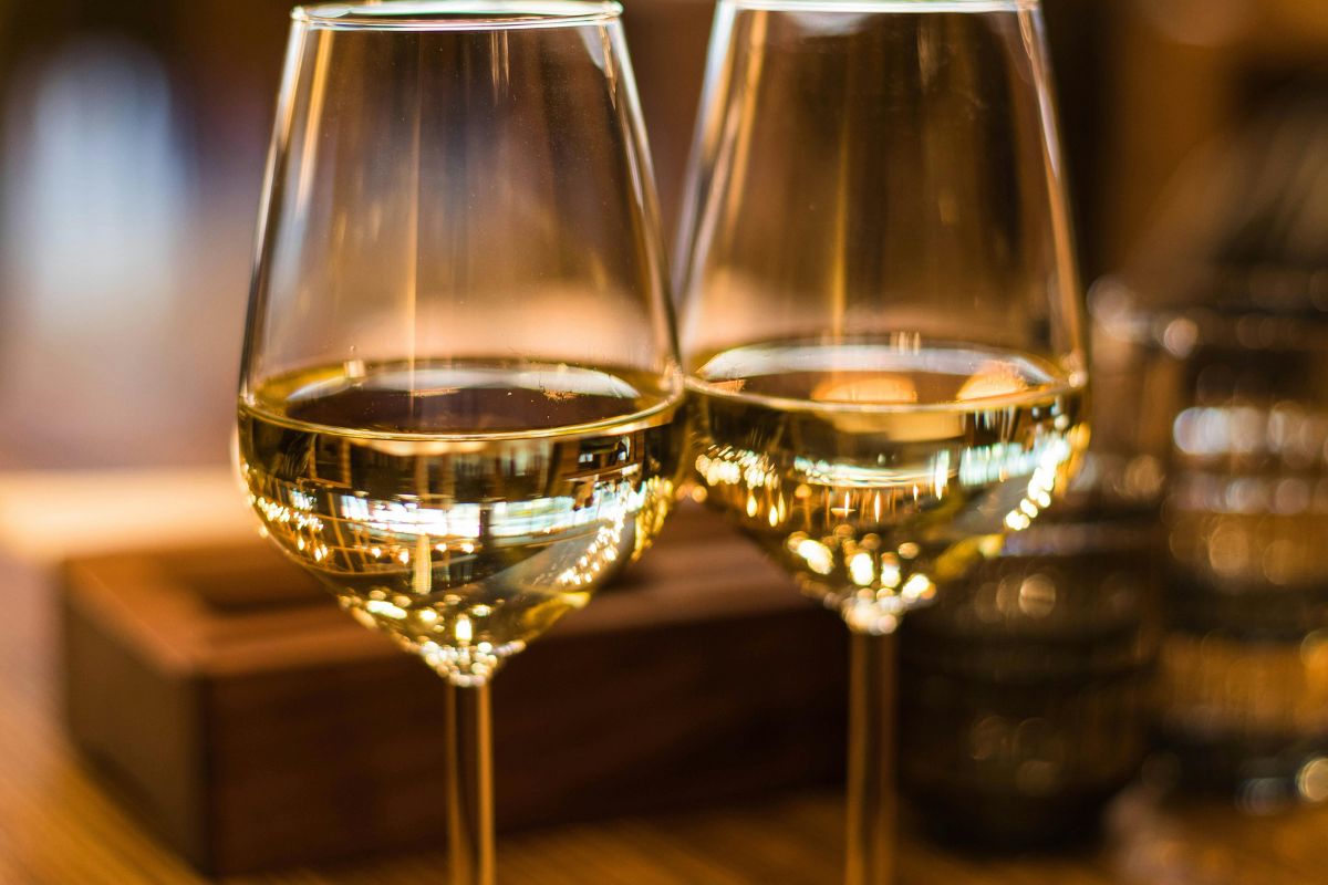 Vino blanco servido en copas de cristal. Foto de Pexels.