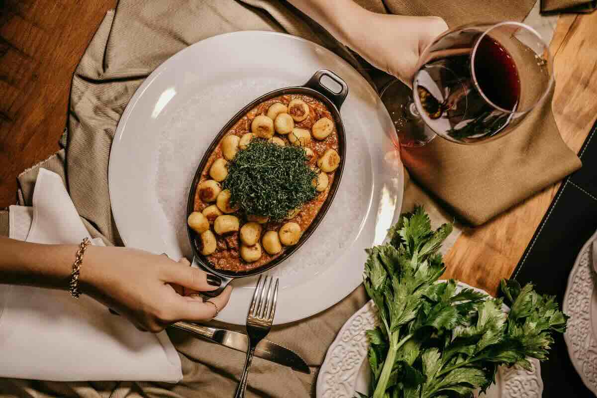 Vino tinto acompañando gnocchi. Foto de Pexels.