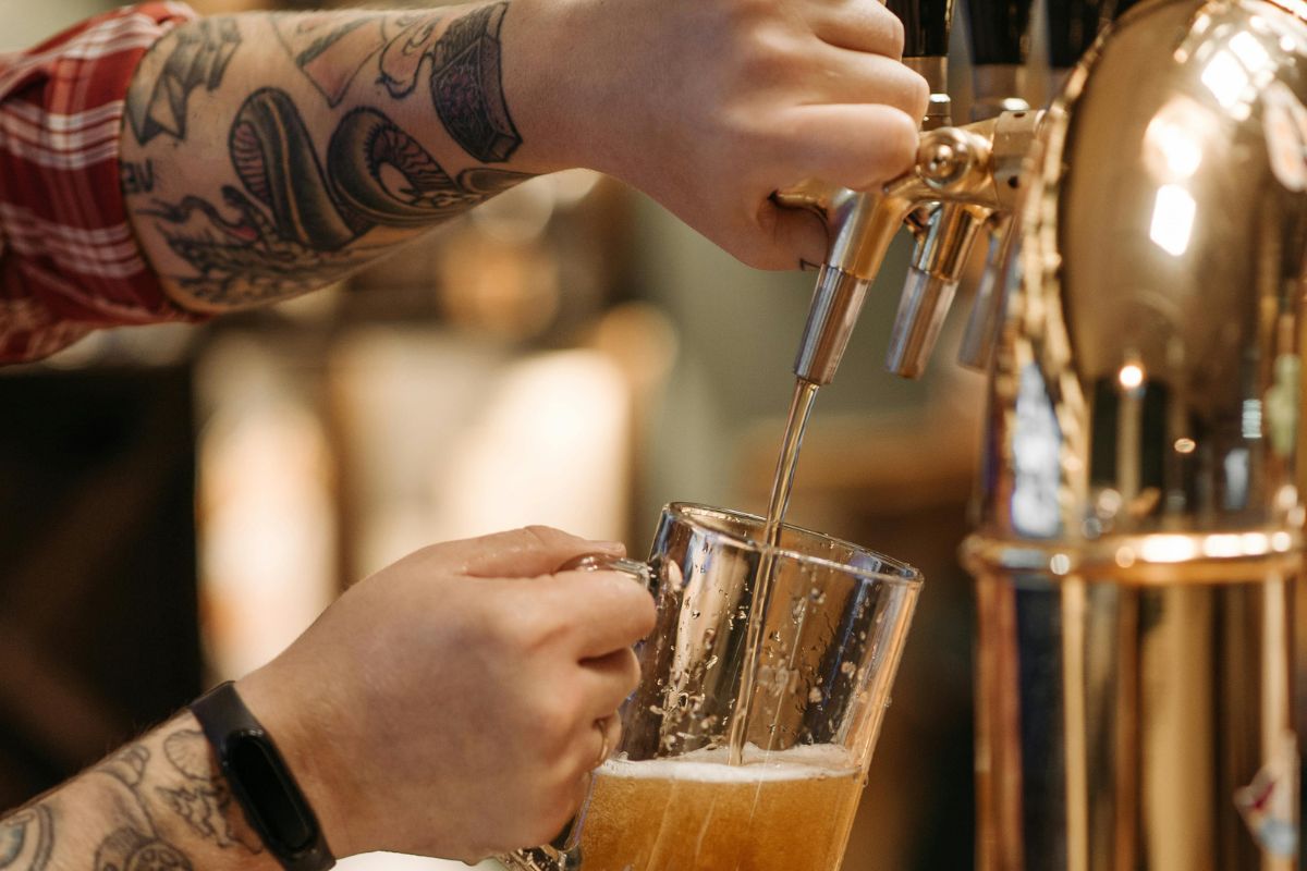 Persona sirviendo cerveza fresca. Foto de Pexels.