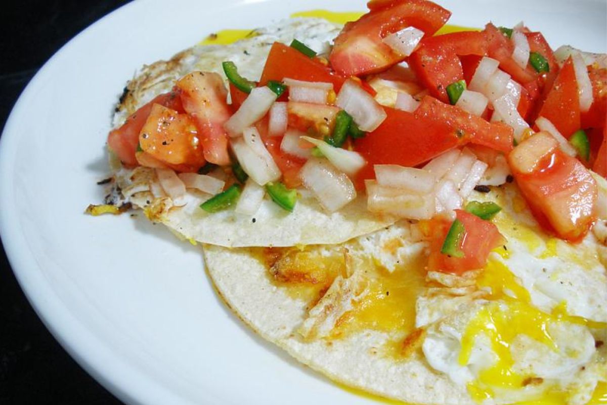 Huevos estrellados con pico de gallo (jitomate, cebolla y cilantro). Foto de Flickr.