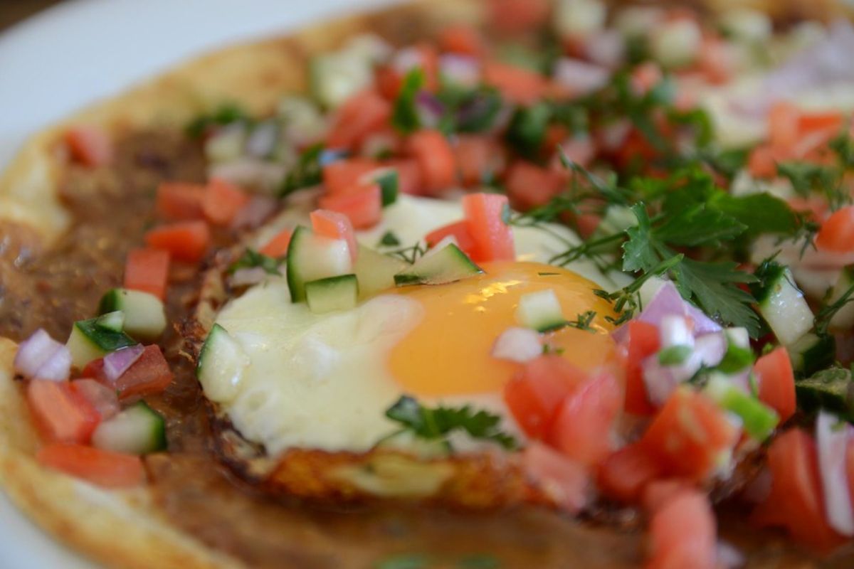 Huevos estrellados con pico de gallo (jitomate, cebolla y cilantro). Foto de Flickr.