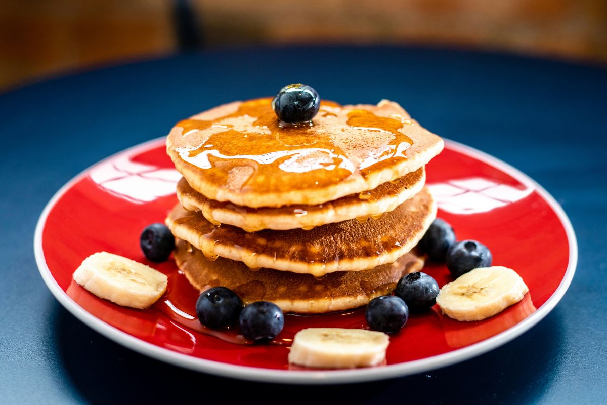 Hotcakes con maple, arándanos y plátano. Foto de Pexels.