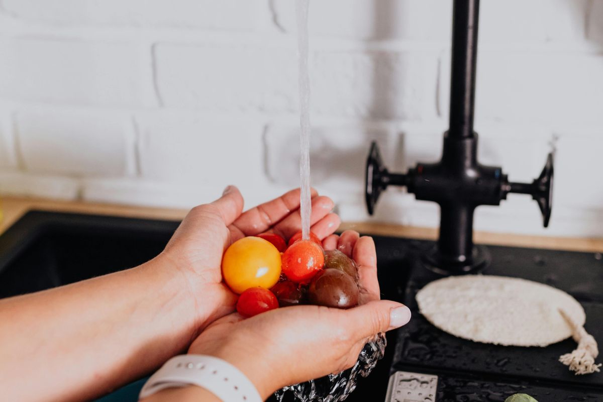 Persona lavando jitomates cherry. Foto de Pexels.