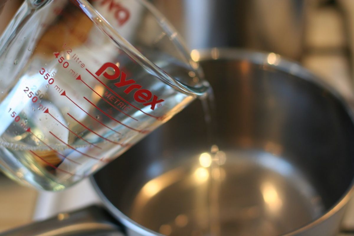 Persona agregando agua a una olla amplia. Foto de Pexels.
