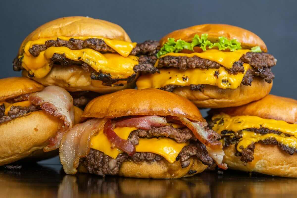 Orden de hamburguesas con queso, tocino y vegetales frescos. Foto de Pexels.