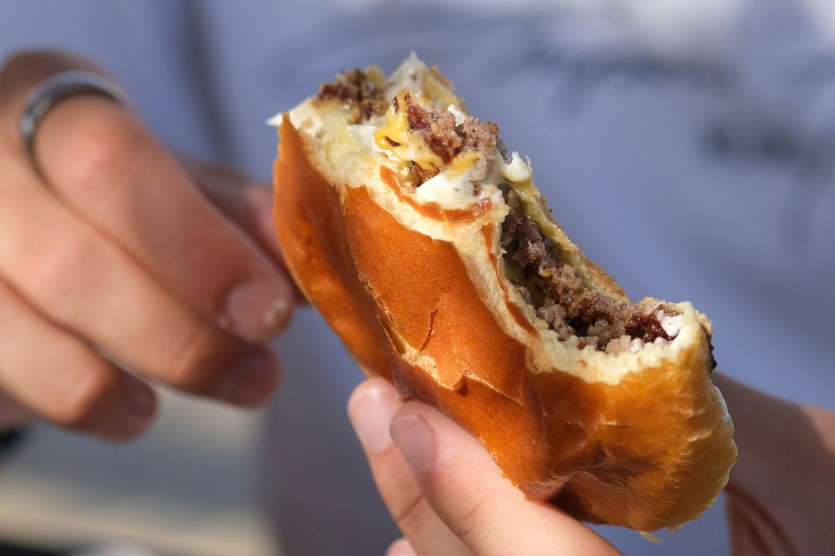 Persona comiendo una smash burger. Foto de Pexels.