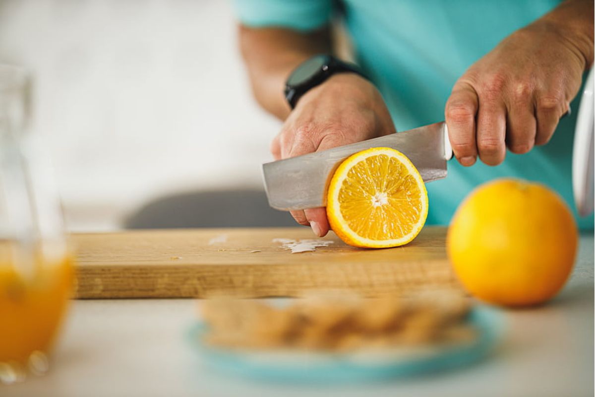 Persona cortando naranja fresca. Foto de Pexels.