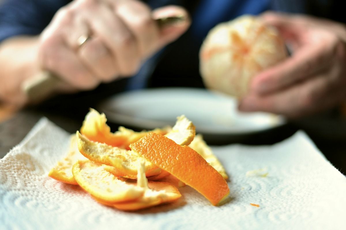 Persona quitando cáscara a mandarina. Foto de Pexels.