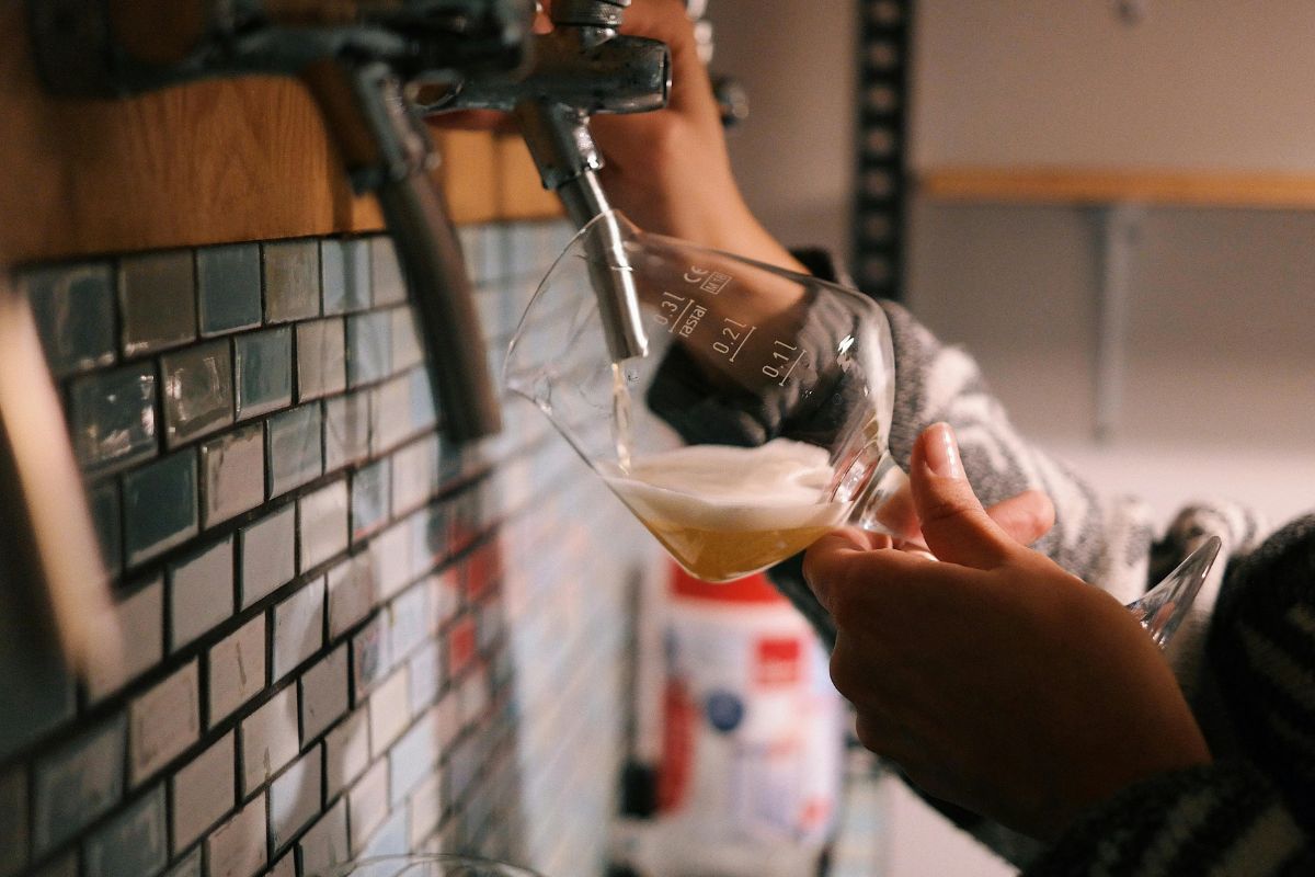 Persona sirviendo cerveza fresca. Foto de Pexels.