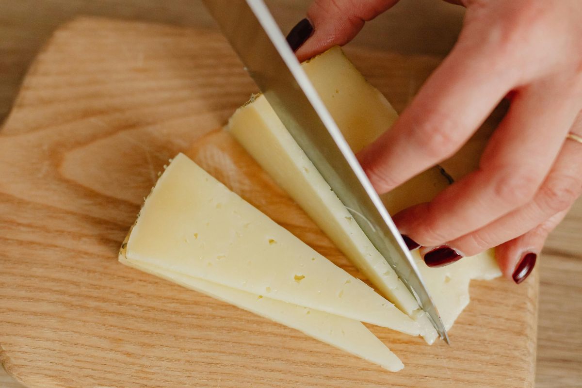 Persona cortando queso fresco. Foto de Pexels.