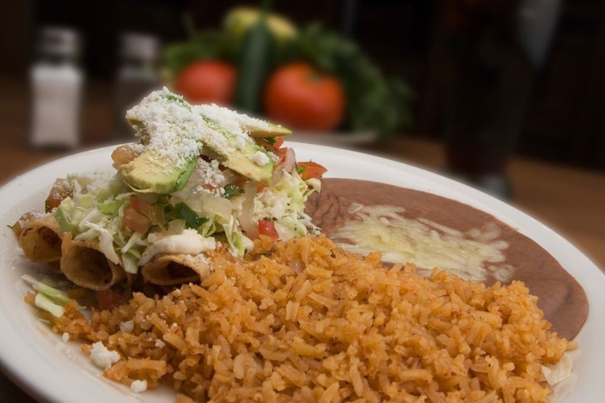Flautas de pollo acompañadas de arroz y frijoles refritos. Foto de Pexels.
