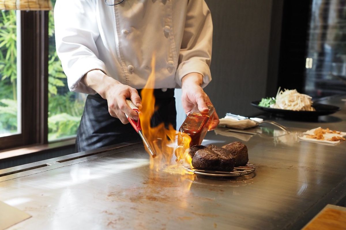 Chef cocinando frente a comensales. Foto de Pexels.