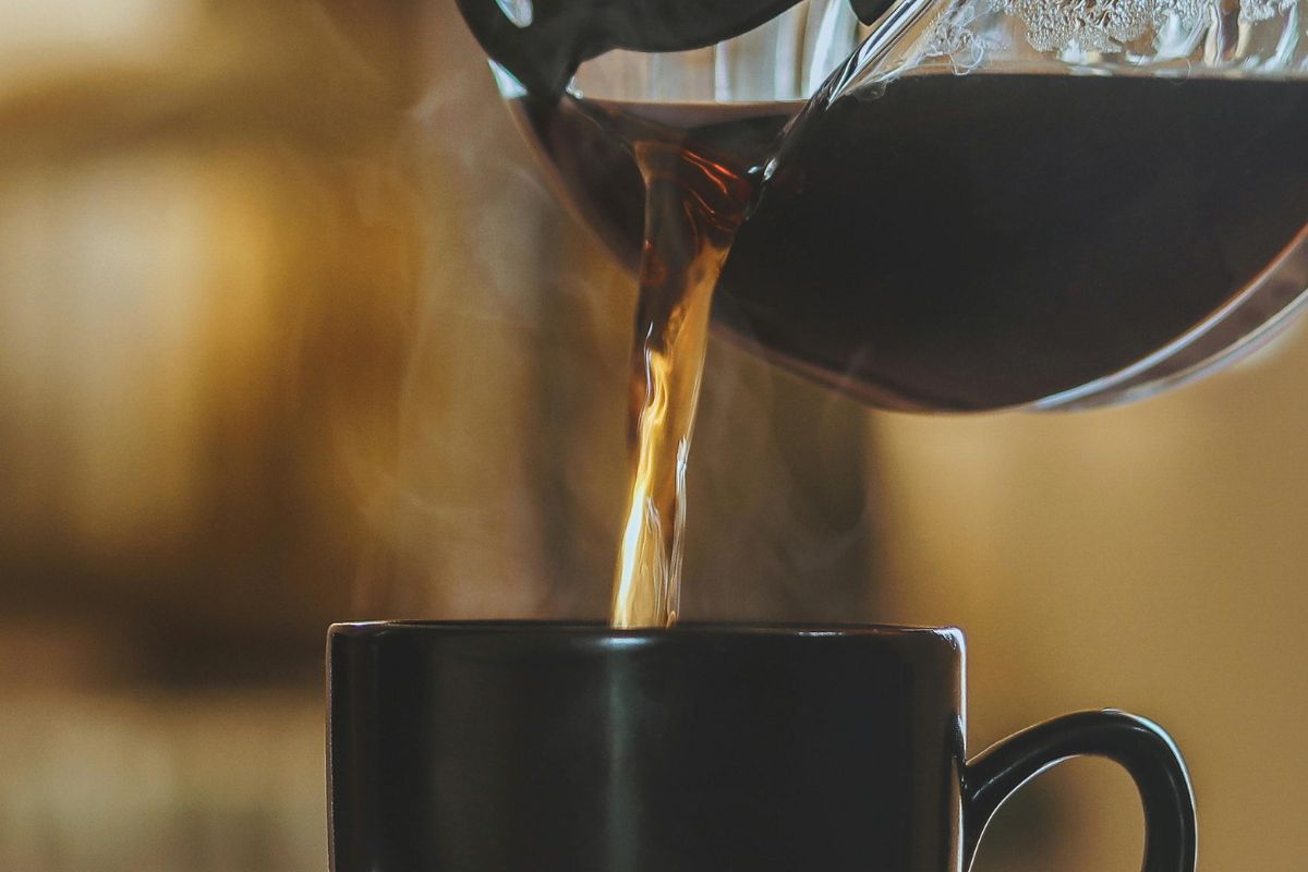 Persona sirviendo café en taza. Foto de Pexels.