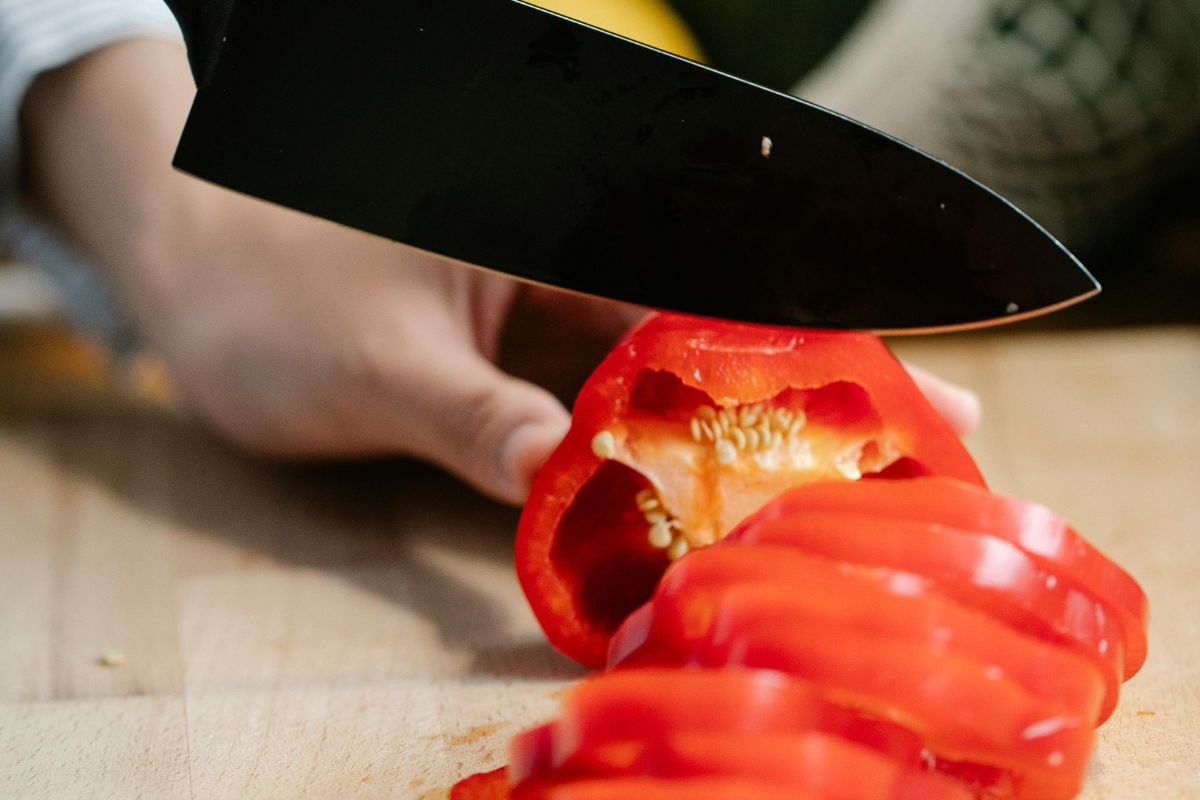 Persona cortando pimiento rojo. Foto de Pexels.